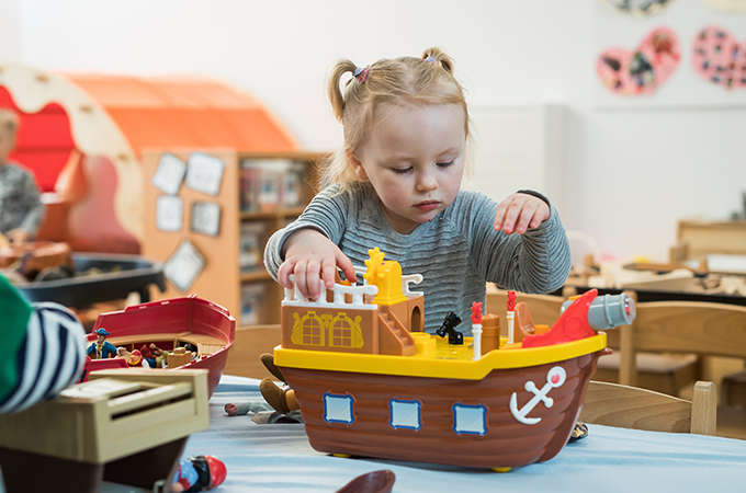 A young child playing with a toy ship in a nursery